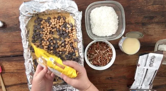 Butterscotch chips being poured over the pan of other ingredients