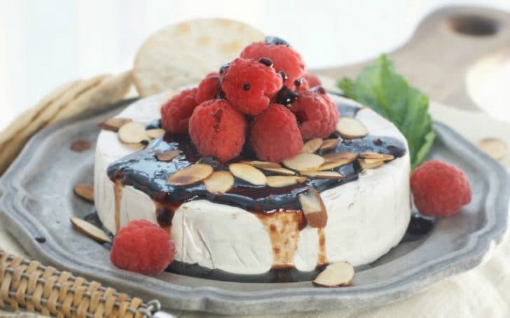 A side view of a whole Toasted Almond Raspberry Baked Brie