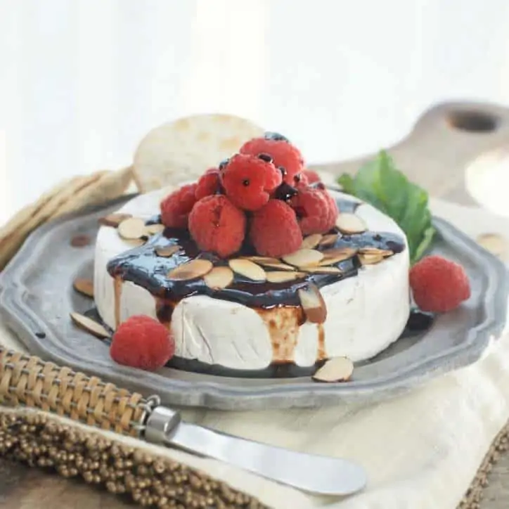 A side view of a whole Toasted Almond Raspberry Baked Brie