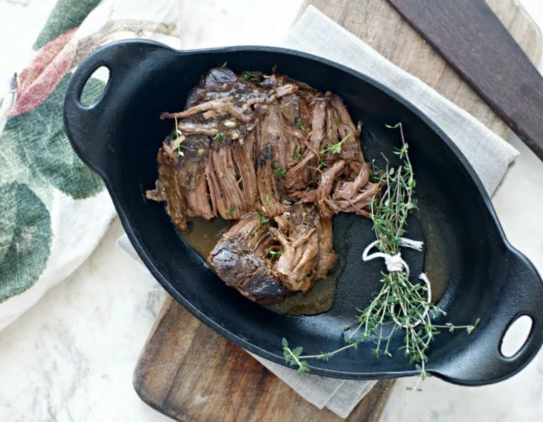 A directly overhead shot of rounded pan sitting on a cutting board with print towel in back ground. Chuck roast in the pan.