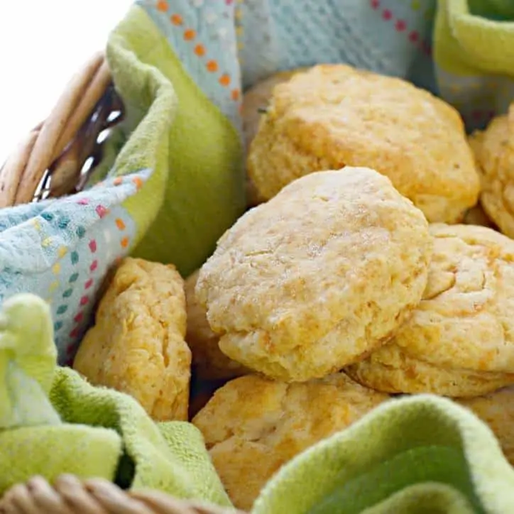 A close up shot of Southern Sweet Potato Biscuits in a basket with a blue and green kitchen towel under them