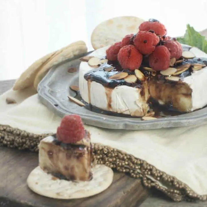 A photo of the Toasted Almond Raspberry Baked Brie with the slice and the wheel of cheese