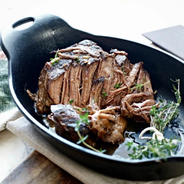 Pot roast in an oblong cast iron pan with thyme