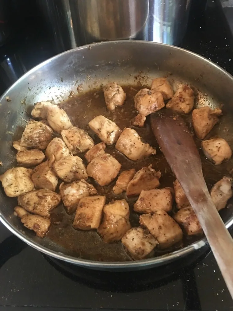 pieces of seasoned chicken cooking in a frying pan