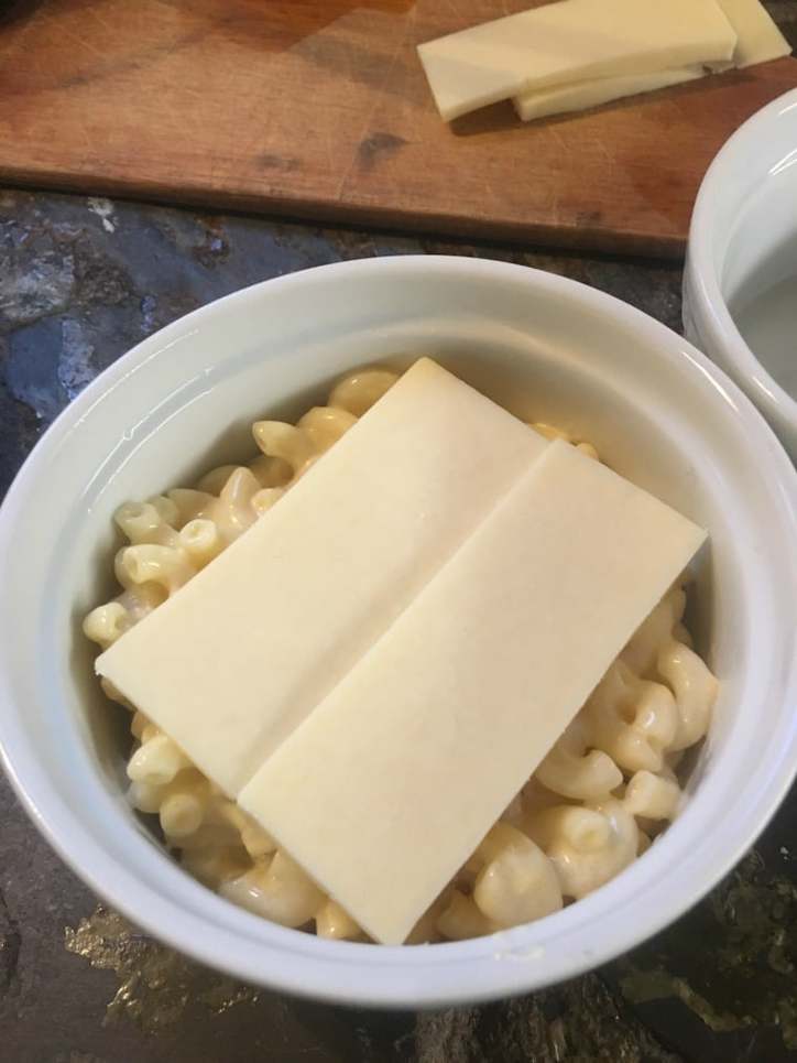 Cheese slices on top of half a ramekin of mac and cheese