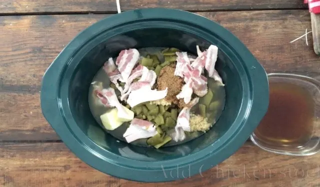 green beans, bacon and other ingredients in the green crock of a crockpot