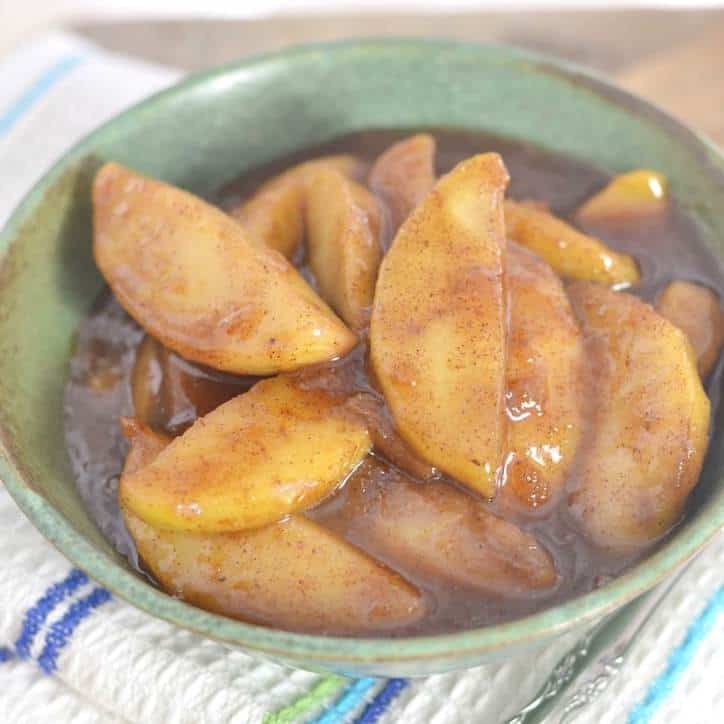 A green ceramic bowl full of cinnamon covered fried apples