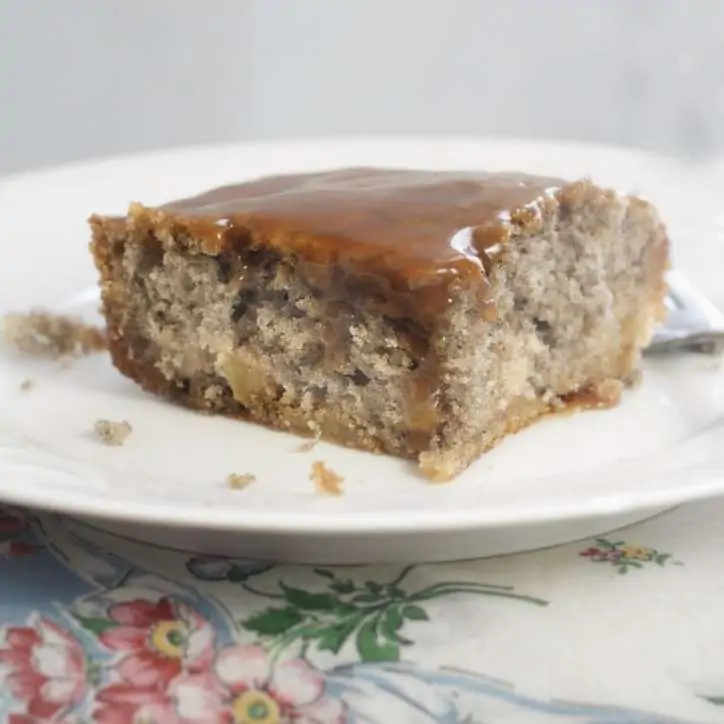 A whole slice of cake sitting with the icing running down the side. Fried Apple Cake with Caramel Icing