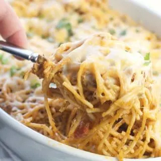 A spoonful of Amazing Baked Taco Spaghetti being scooped from the dish with cheese pulls