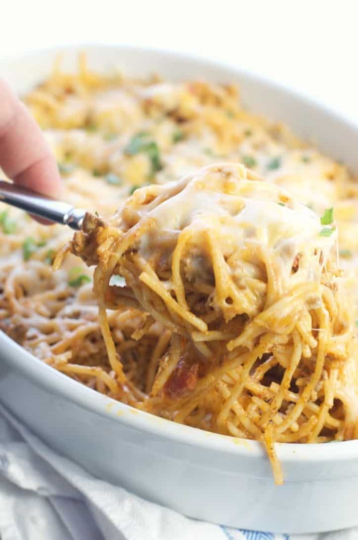 A spoonful of this dish being scooped from the baking dish with cheese pulls