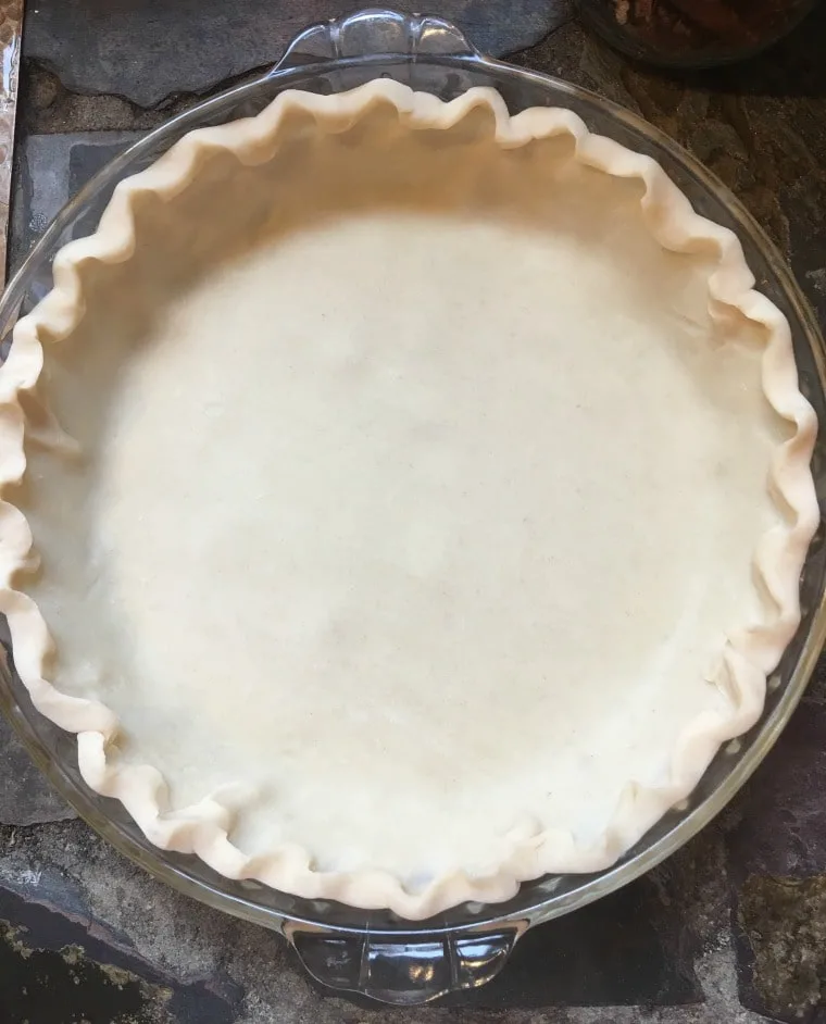 A photo of the pie crust with the edges fluted and ready to receive the pie ingredients.