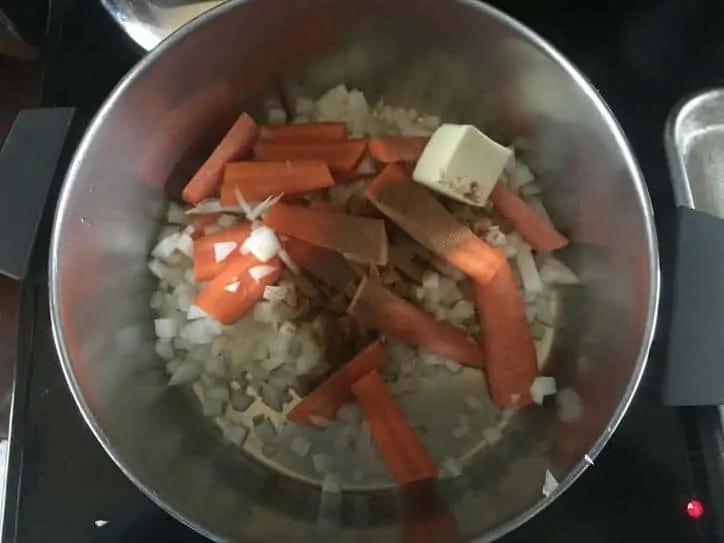 onions, carrots and a pat of butter in a stock pot on the stovetop