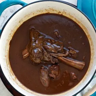 A photo of the prepared dish in the dutch oven from overhead Lamb Shanks in Wine Sauce
