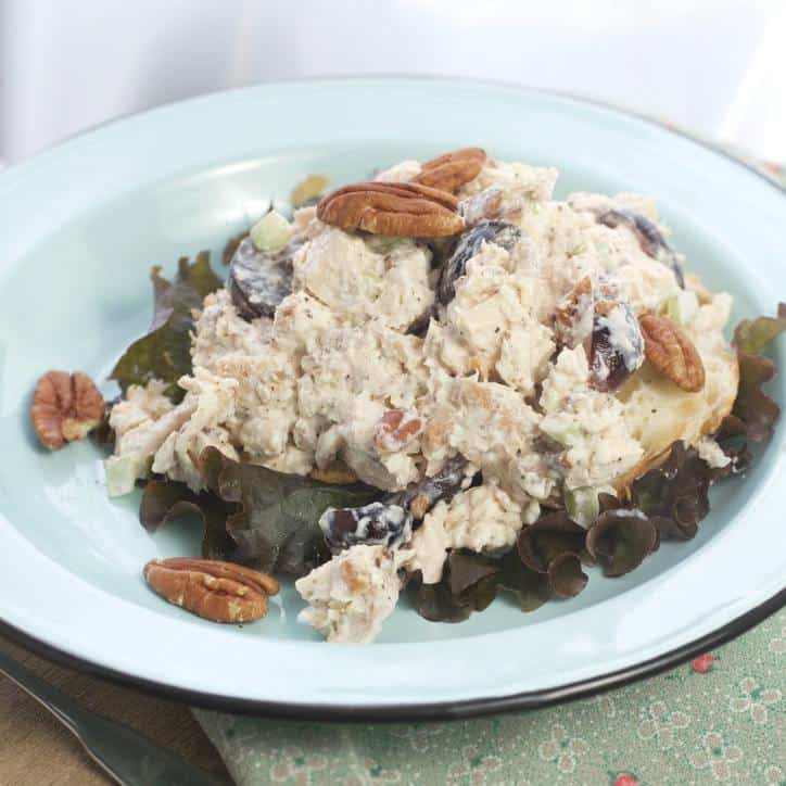 Chicken salad on a bed of lettuce with pecans strewn about the plate