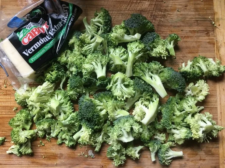 broccoli chopped and ready for blanching on cutting board with cheese