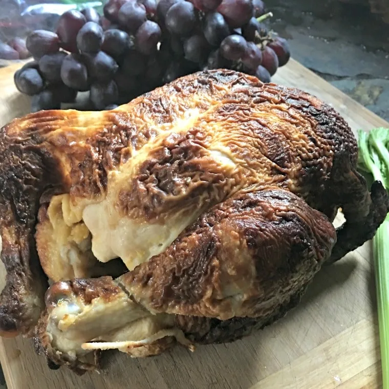A photo of the rotisserie chicken, purple grapes and a celery stalk on cutting board