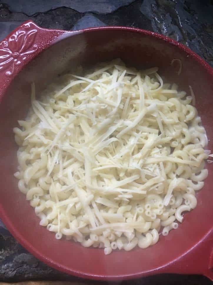 A photo of shredded cheese scattered over the noodles for easy baked macaroni and cheese