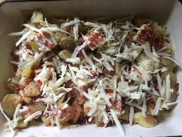 potatoes, cheese and bacon bits in a baking pan