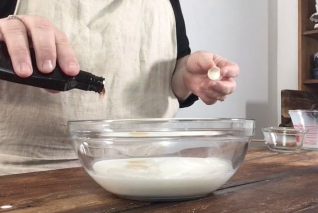 A photo of Wendi pouring vanilla into the half and half mixture in a glass bowl