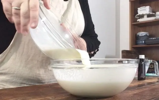 pouring the contents of one medium sized glass bowl into the larger glass bowl