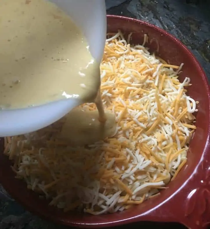 A photo of the mixture being poured over the noodles and cheese for easy baked macaroni and cheese