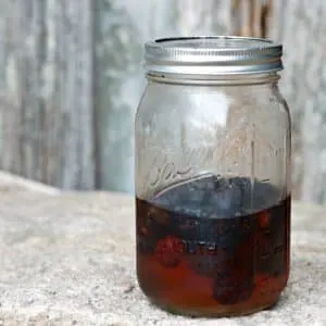 A photo of blackberries in the pickling liquid in a Mason Jar