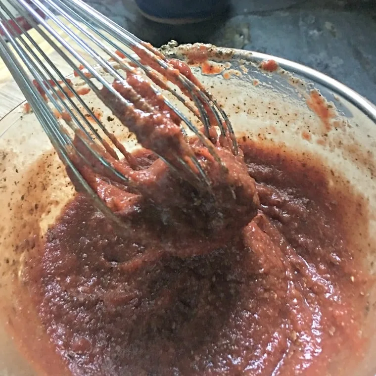 The ingredients for easy pizza sauce from scratch showing the thickness of the sauce