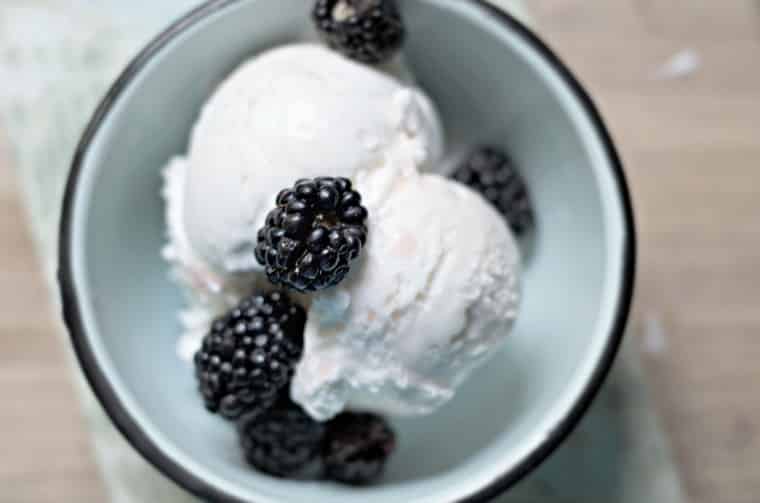 A photo from above of pickled blackberries over the top of icecream in blue bowl