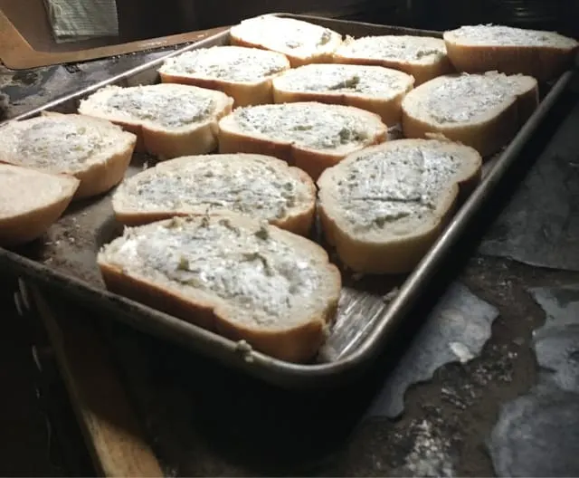 Herbed butter spread on the bread and placed in baking sheet