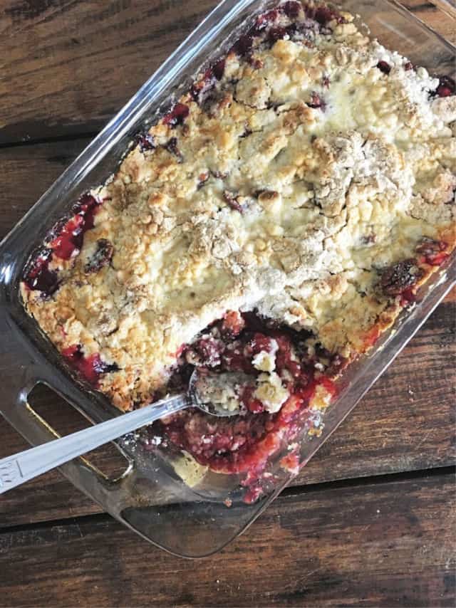 A rectangular pan of cherry cobbler with a spoon in it
