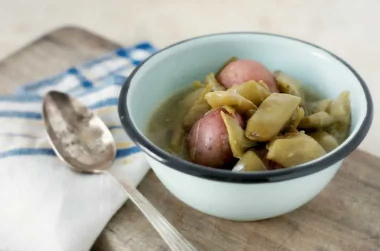 green beans and new potatoes in a blue bowl with napkin and spoon