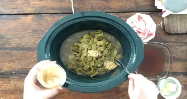 Adding all of the ingredients to the green crockpot bowl