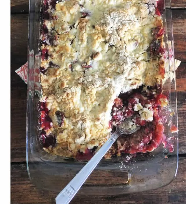 Close up of 9x13 pan with baked cherry cobbler and spoon