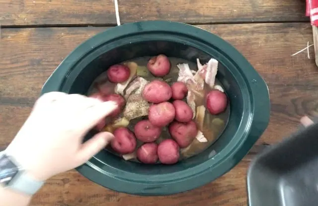 placing the new potatoes in the crockpot on top of the green beans