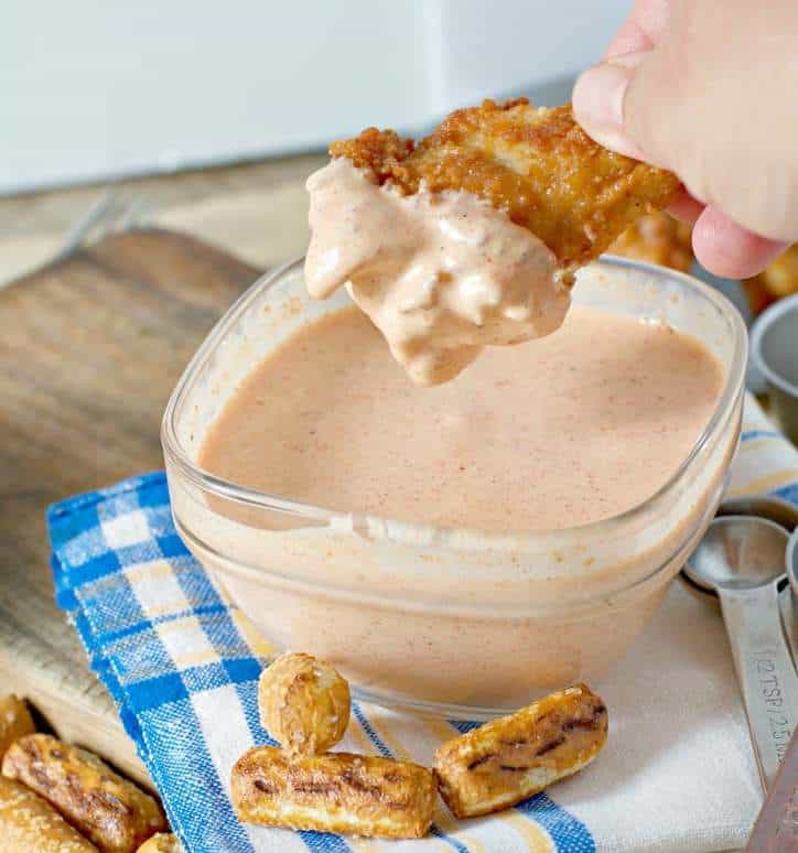 A photo of a chicken wing being dipped in Appalachian Mountains Tiger Sauce