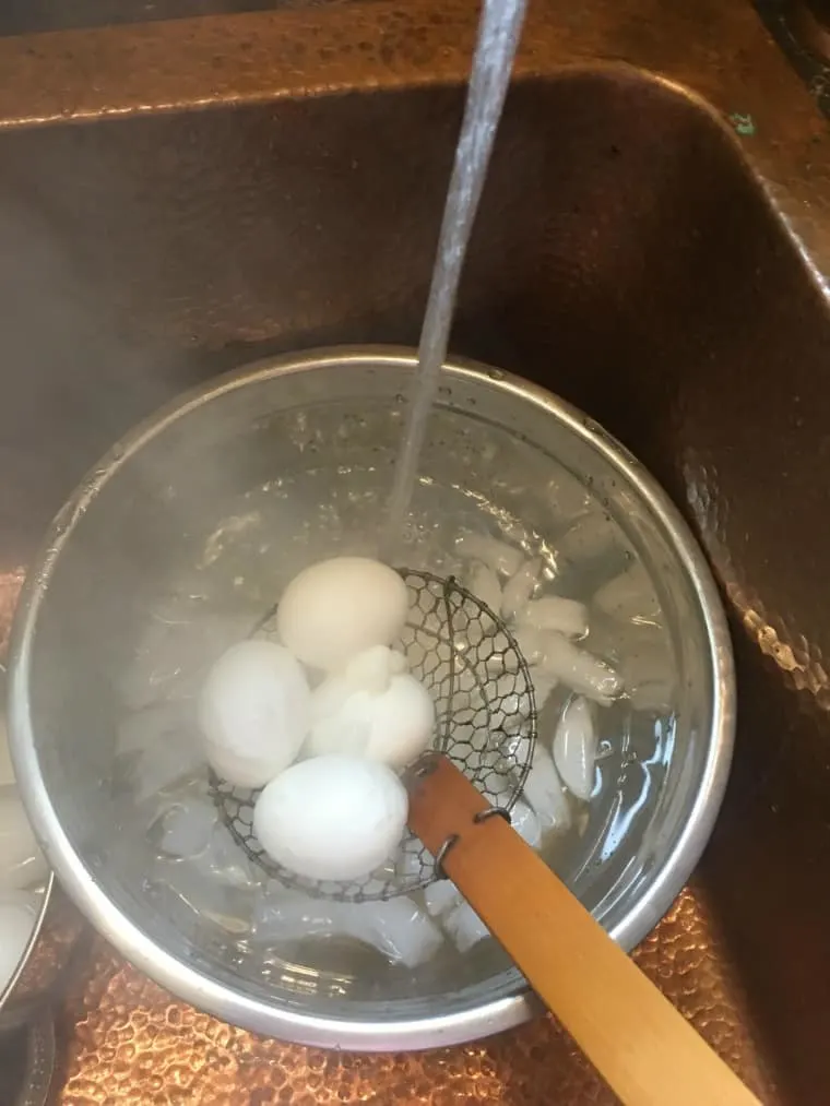 A photo of 4 eggs going into an ice bath with water running over them