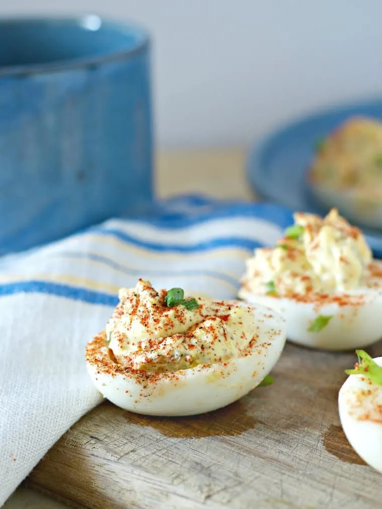 A side view of some southern deviled eggs on cutting board with blue napkin