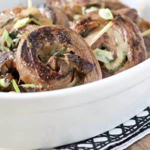 A close up view of a Barbecue Flank Steak Roll Ups in a white dish