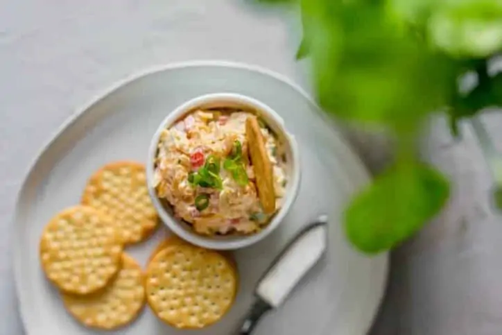 A small white bowl with crackers and knife