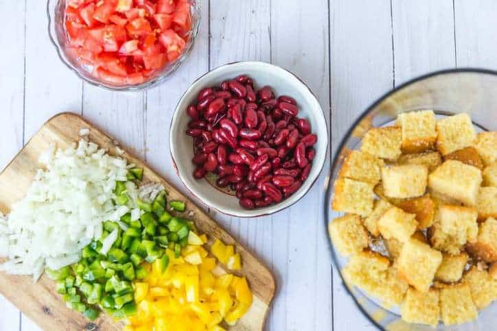 small bowls of tomatoes, kidney beans and cutting board of onions and peppers.