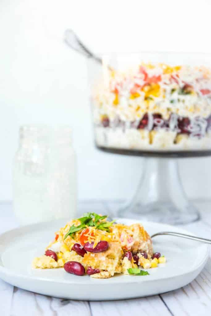 A photo of a plate of cornbread salad with the trifle bowl in the background