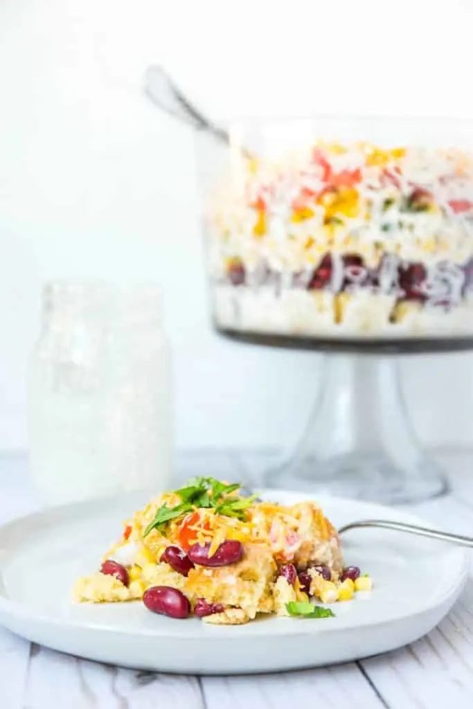 A photo of a plate of cornbread salad with the trifle bowl in the background