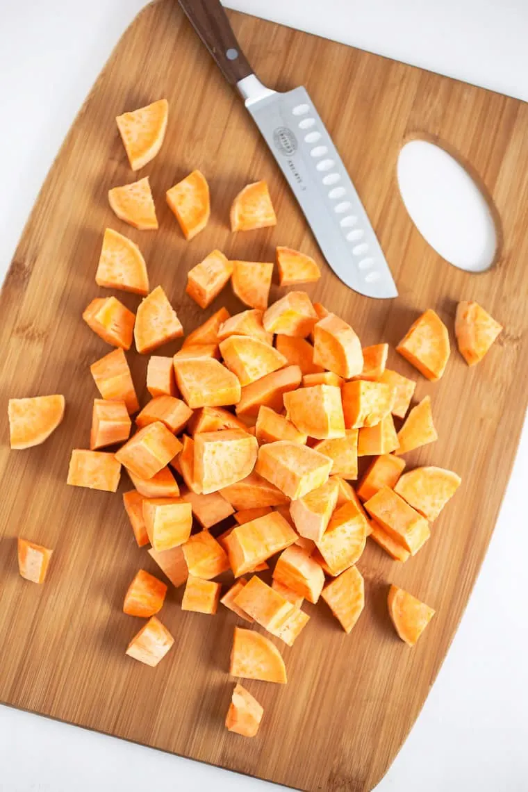 A sweet potato cut up in 1 inch pieces for southern sweet potato casserole on cutting board