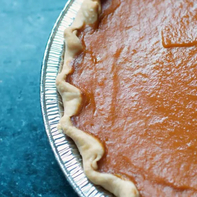 close up of the edge of a pumpkin pie on a gray table