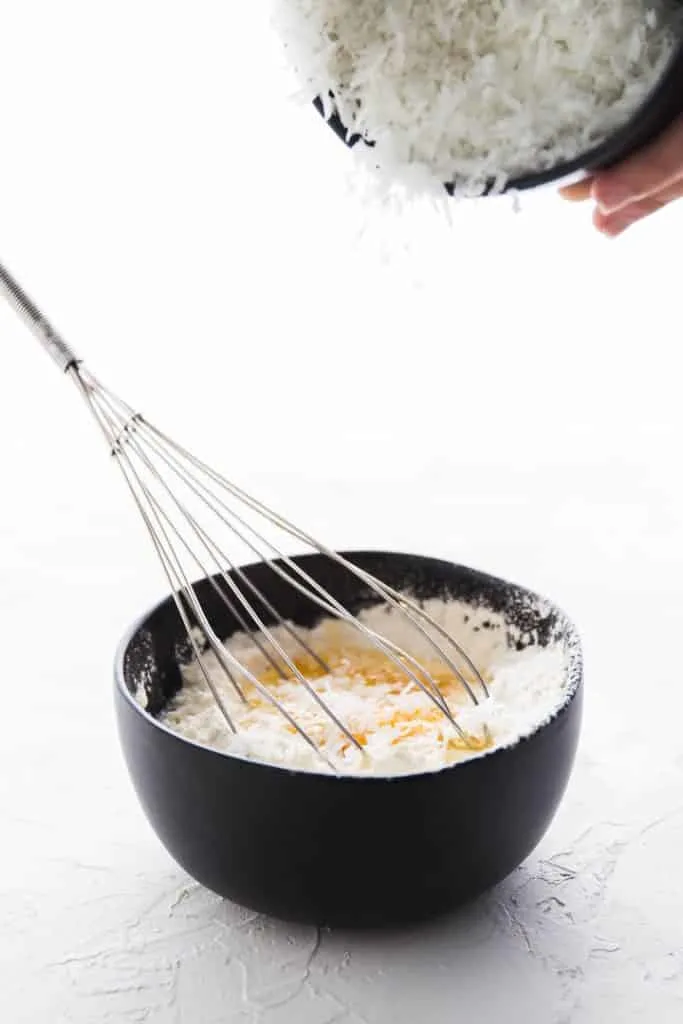 Sprinkling the coconut into the coconut custard pie filling mix