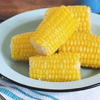 A plate of yellow corn on the cob sitting on a blue plate