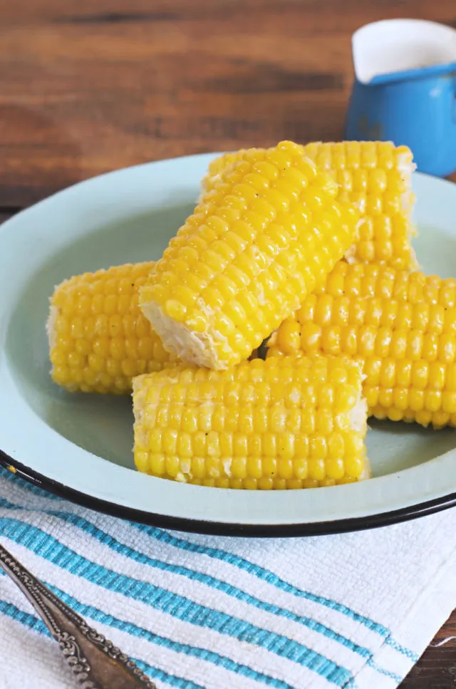 A plate of yellow sweet corn on the cob sitting on a blue plate
