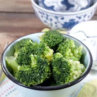 Bowl of broccoli with a patterned blue bowl in the back ground for how to cook frozen broccoli