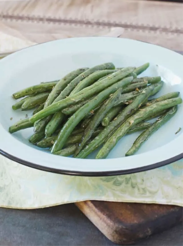 Blue plate of green beans and blue green kitchen towel for how to saute green beans