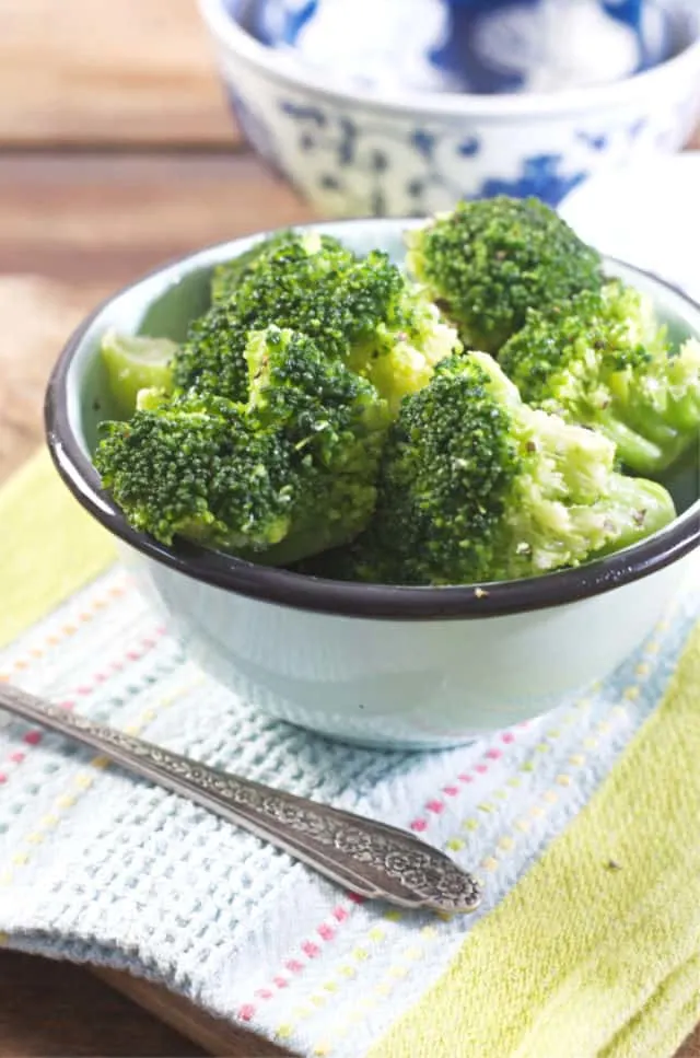 A blue bowl of veggie with fork in foreground